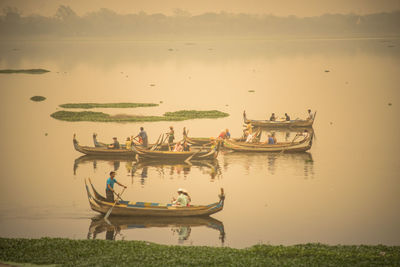 Boats in lake against sky during sunset