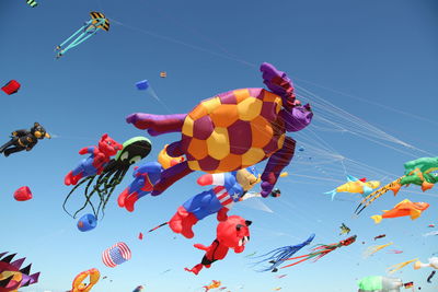 Assortment of colorful kites flying in clear blue sky