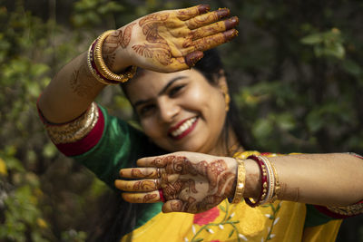 Indian woman with smiling face showing palms painted with mahendi or myrtle
