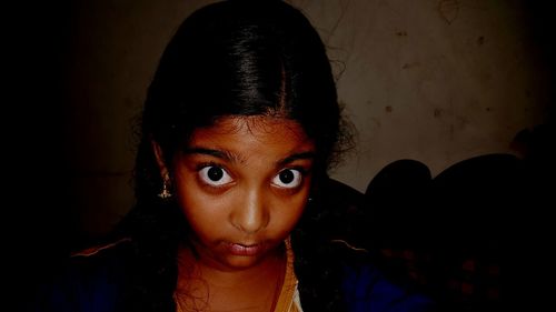 Close-up portrait of girl against wall at home