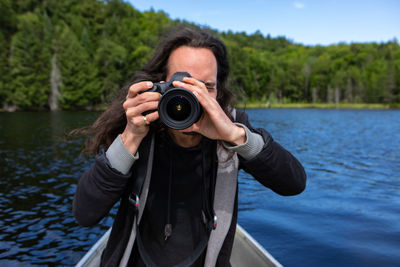 Portrait of man photographing against lake