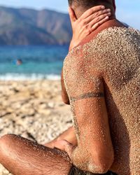 Midsection of man with sand on wet body