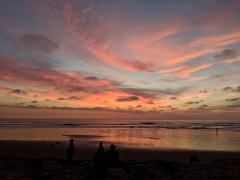 Silhouette people on beach against sky during sunset