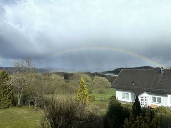 Scenic view of rainbow over houses and trees against sky