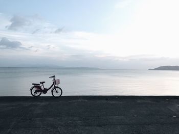 Bicycle by sea against sky