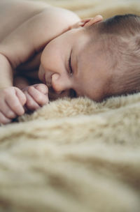 Close-up of shirtless baby girl sleeping on bed