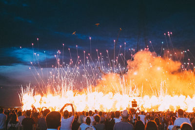 Crowd at music concert against sky at night