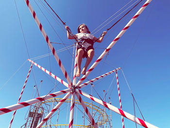 Low angle view of girl against blue sky