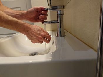 Cropped image of man washing hands in bathroom sink