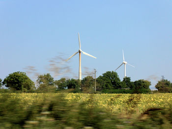 Wind turbines on field against clear sky