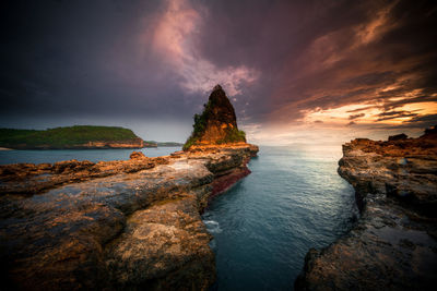 Panoramic view of rocks on sea against sky during sunset