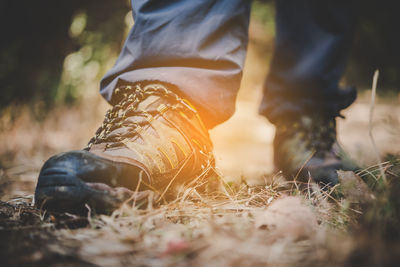 Low section of man wearing hiking boots on field