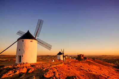 Traditional windmill on land against sky during sunset