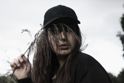 Close-up of woman holding plants against sky