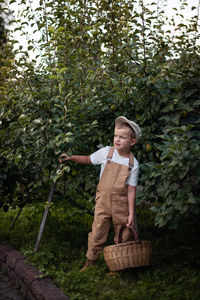 Full length of girl standing by basket against trees