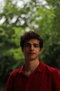 Portrait of young man standing against trees