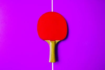Directly above shot of red table tennis racket on purple table
