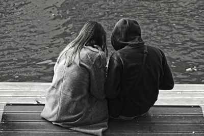 Rear view of couple sitting on pier