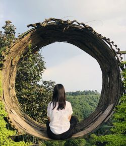 Rear view of woman sitting against sky