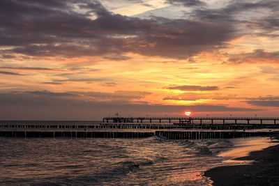 Pier on sea against cloudy sky