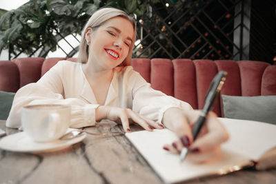 Midsection of woman with coffee while sitting on table