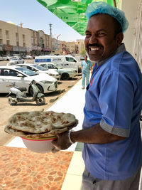 Portrait of smiling man standing on car