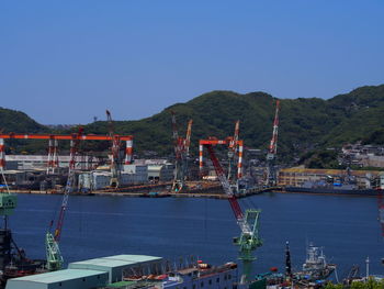 Boats moored at harbor against clear blue sky