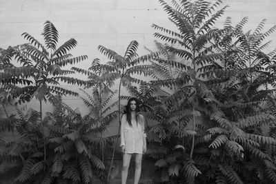 Full length of young woman standing against palm trees