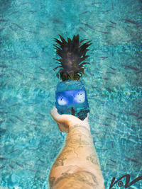 Man holding umbrella by swimming pool