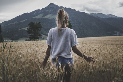 Rear view of woman standing in wheat field