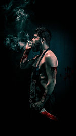 Man smoking cigarette against black background