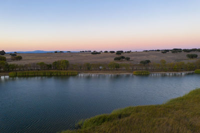 Scenic view of lake against clear sky during sunset