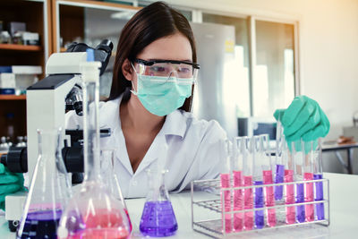 Female scientist holding test tube at table in laboratory