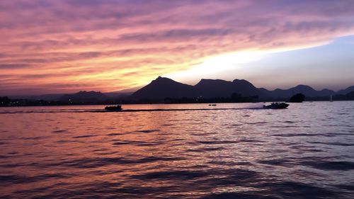 Scenic view of lake against dramatic sky during sunset