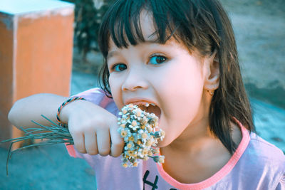 Portrait of girl eating flower outdoors