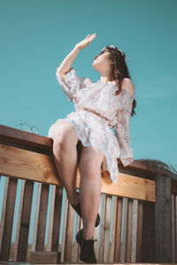 Low angle view of woman sitting on seat against sky