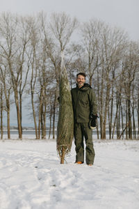 Man standing with christmas tree at winter
