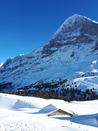 Scenic view of snow covered mountains against blue sky