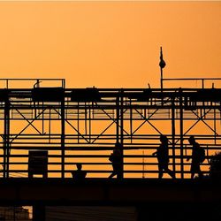 Silhouette people on bridge against sky during sunset