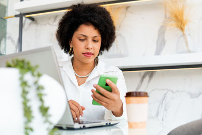 Young woman using mobile phone while sitting on table