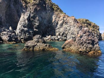 Rock formations by sea against sky