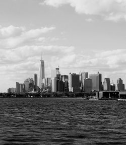 City at waterfront against cloudy sky