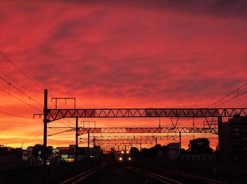 Silhouette railroad tracks against dramatic sky during sunset