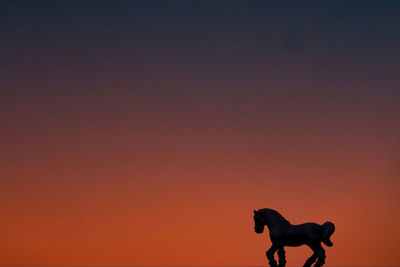 Silhouette of a horse against orange sky