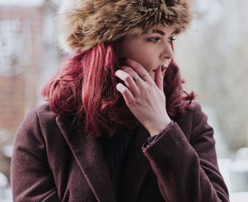 Close-up of young woman in warm clothing standing outdoors