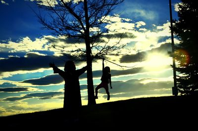 Silhouette people playing on beach against sky during sunset