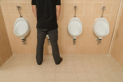 Low section of man urinating in public restroom