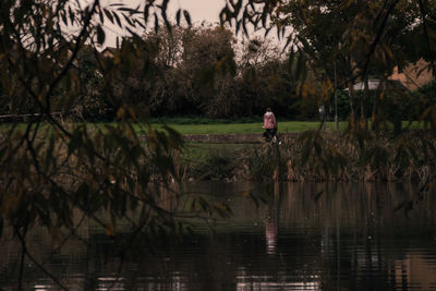 Reflection of man in lake against trees