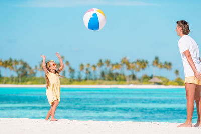 Full length of father and daughter playing with ball at beach