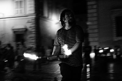 Man holding fire while standing on street at night